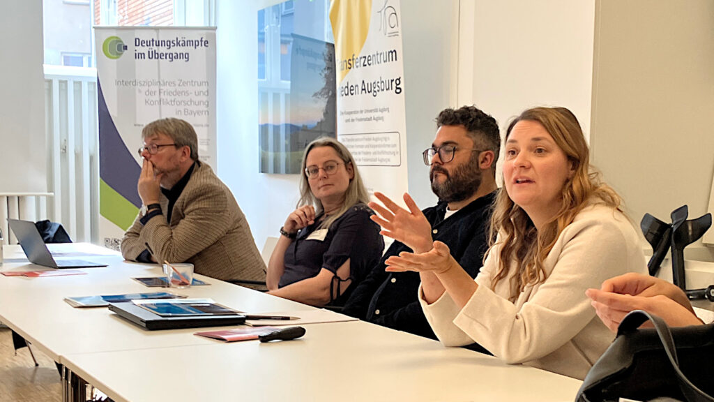 Lilli Banholzer stellt die Bayerische Wissenschaftsallianz für Friedens-, Konflikt- und Sicherheitsforschung (FoKS) vor. Neben ihr sitzen Gregor Walter-Drop (Friedensakademie Rheinland-Pfalz), Julia Reichenbacher (Transferzentrum Frieden Augsburg - TFA) und Timo Lowinger (FoKS), v.l.n.r.